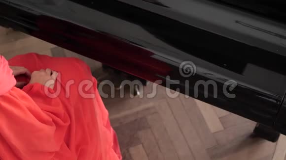 一个面目全非的女人穿着一件红色的长裙打开了钢琴的盖子视频的预览图