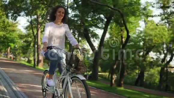快乐微笑的女人正在享受她的时光在黎明时骑着一辆城市自行车里面有篮子和鲜花视频的预览图