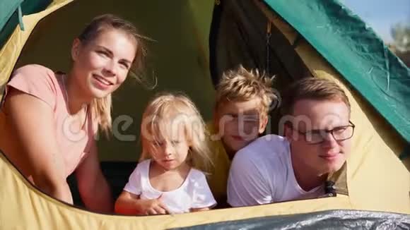 坐在帐篷里看着与大自然的距离的年轻一家人很幸福视频的预览图
