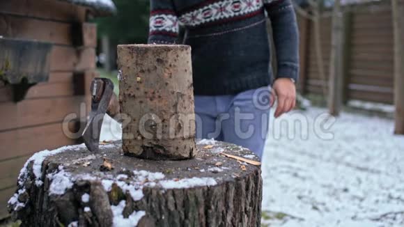 一个英俊的年轻人在冬天用斧子砍木头的慢动作视频的预览图