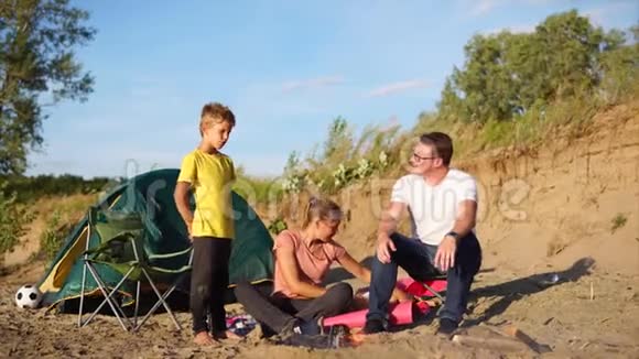 一个有孩子的小家庭在火灾周围取暖夏天在大自然上搭帐篷视频的预览图