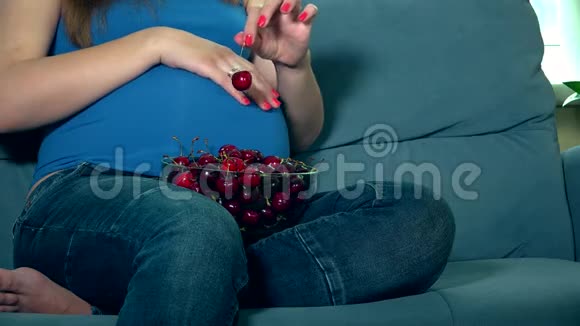 准妈妈的手抚摸着巨大的肚子吃樱桃浆果视频的预览图