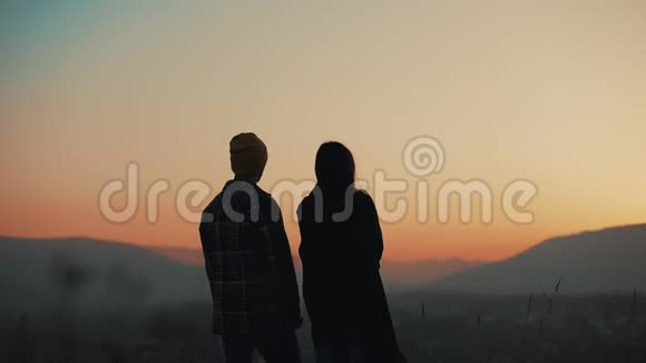 恋爱中的年轻夫妇在山上欣赏日落的剪影假期旅行浪漫求婚视频的预览图