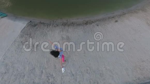 快乐的小女孩在河边的海滩上绕着自己转视频的预览图
