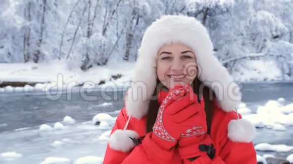 冬天森林里一条山河附近的美女画像女人揉着他的手呼吸着温暖视频的预览图