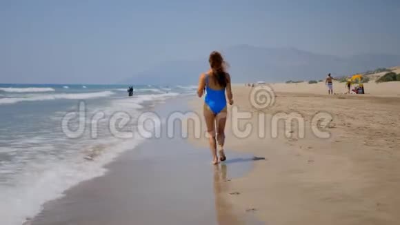 年轻女子在沙滩上奔跑视频的预览图