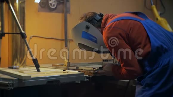 穿红色衬衫戴防护面罩的人进行焊接工作视频的预览图