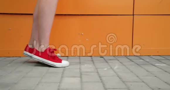 穿红色运动鞋的女孩腿沿着橙色的墙跑视频的预览图