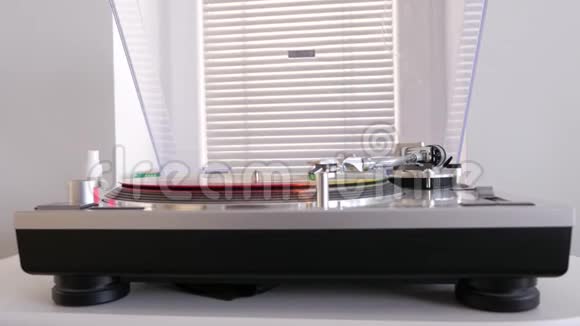 现代的乙烯唱片播放器靠近一扇带百叶窗的窗户视频的预览图