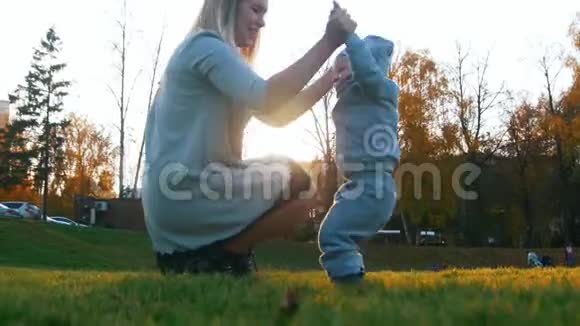 年轻的妈妈穿着裙子和她的小宝宝在秋天公园玩幸福家庭视频的预览图
