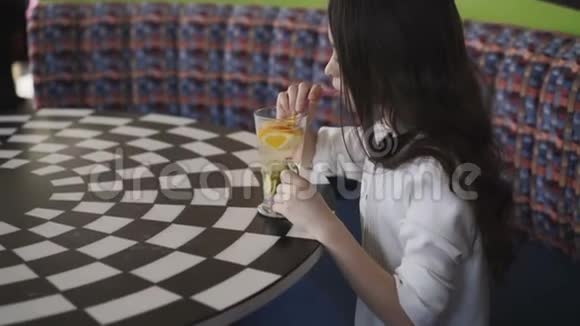在咖啡馆里用小管搅拌柠檬水的漂亮女孩视频的预览图