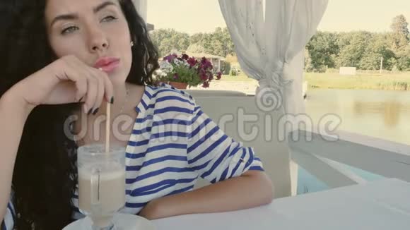 漂亮的女人喝咖啡在夏季露台欣赏河景视频的预览图