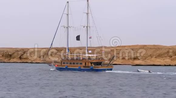 美丽的旅游游艇在岩石的背景下在波涛汹涌的大海中航行埃及视频的预览图