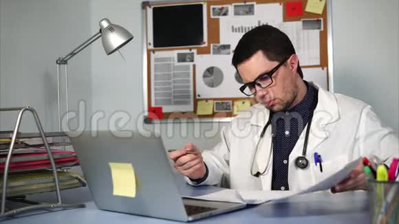 一位年轻的医生在一天结束时在综合诊所签了文件视频的预览图