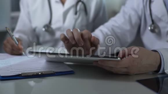 医生坐在桌子旁处理药片和纸表格团队合作视频的预览图