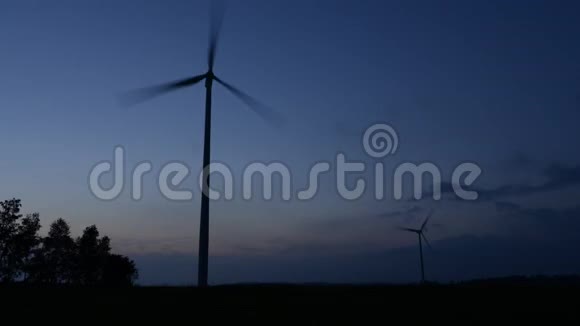 剪影式风力涡轮机农场覆盖着黄昏的天空和白云旋转风力发电厂时间表视频的预览图