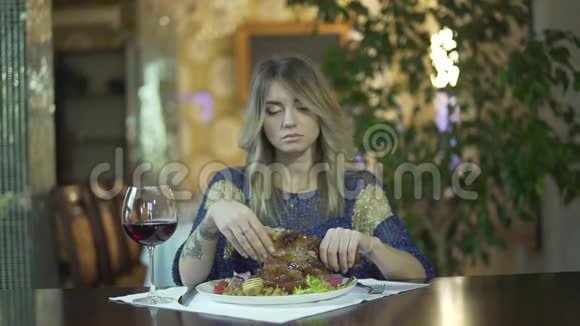 年轻漂亮的纹身金发女孩在高档餐厅撕肉用手指吃不当行为视频的预览图