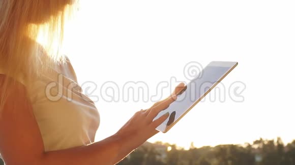 女人在日落时使用数字平板电脑慢动作视频的预览图