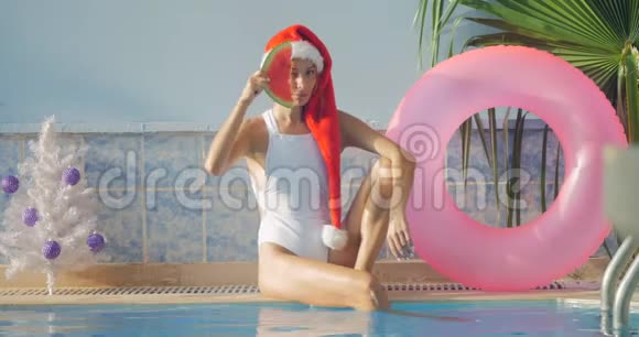 穿着泳衣戴圣诞帽的年轻女子新年主题视频的预览图