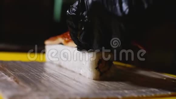 厨师用鱼做寿司卷的特写框架戴手套的专业厨师把鳗鱼放在寿司卷上视频的预览图