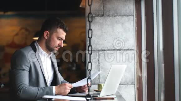 英俊的年轻商人在早餐时在咖啡馆里放松在检查电子邮件或短信时输入通用笔记本电脑视频的预览图