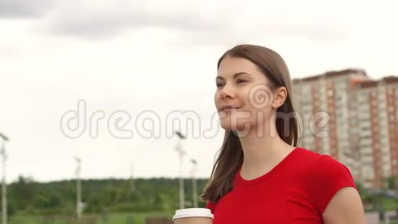 女人在公园里散步喝咖啡放松暑假微笑面对背景房子视频的预览图