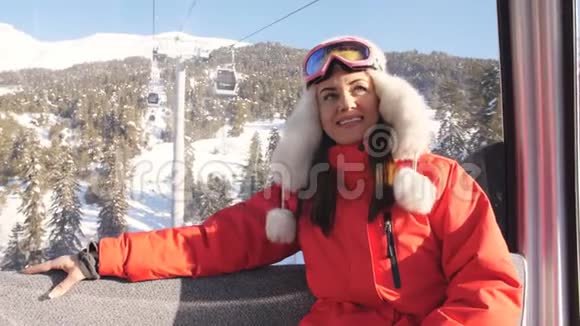 滑雪场女孩乘坐滑雪缆车舱欣赏美丽的白雪覆盖的风景视频的预览图
