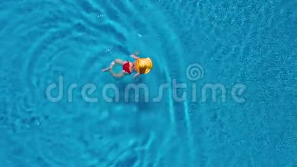 从顶部看一个穿着红色泳衣和一顶黄色大帽子的女人在游泳池里游泳视频的预览图