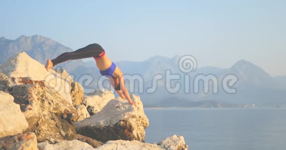 运动的女人在岩石上做瑜伽视频的预览图