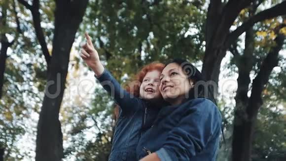 一位美丽的妈妈和她可爱的女儿正在秋天的公园里散步妈妈把女儿抱在怀里他们视频的预览图