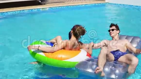 年轻有魅力的人在游泳池聚会上用充气管游泳漂亮的女人和男人有泳池派对视频的预览图