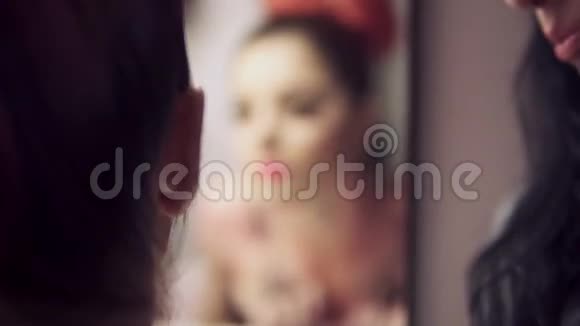 美丽的年轻模特假睫毛在镜子里看着自己同时准备参加时装秀化妆视频的预览图