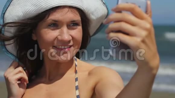 快乐的年轻女子在海边海滩自拍在智能手机上拍照视频的预览图