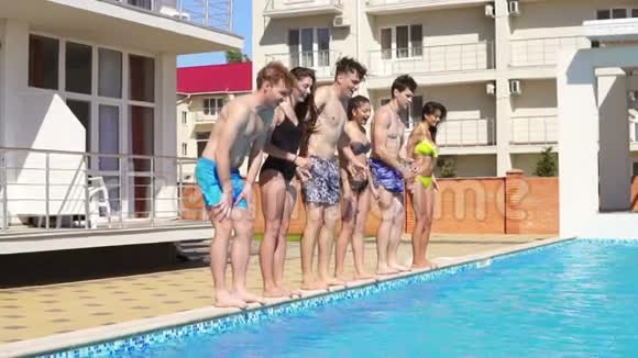 一群穿着泳衣的年轻人在夏天跳进游泳池慢镜头视频的预览图