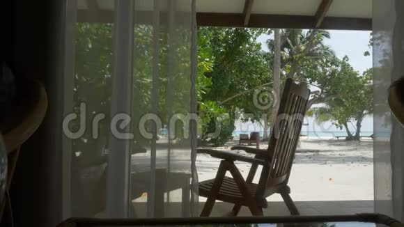 窗户有窗帘俯瞰美丽的海滩有棕榈树和海洋视频的预览图