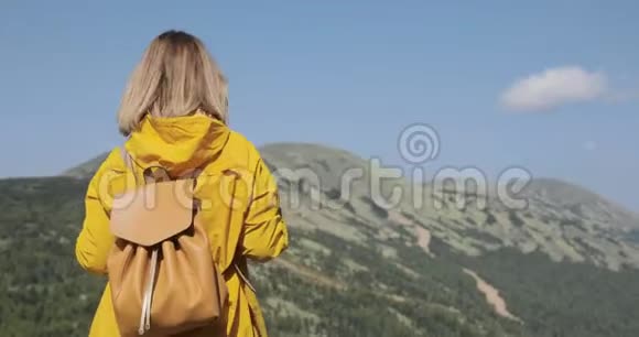 带背包的年轻姑娘在山顶欣赏风景视频的预览图