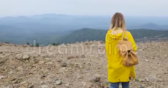 穿着黄色雨衣在山上徒步旅行的健康时髦人士视频的预览图
