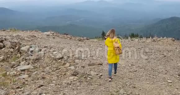 穿着黄色雨衣在山上徒步旅行的健康时髦人士视频的预览图