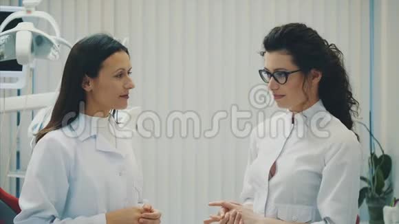 办公室里有两个牙医年轻漂亮的女人站着说话穿着医用白色衣服视频的预览图