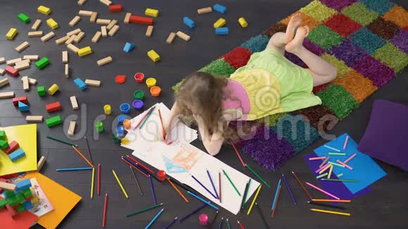 漂亮的女孩子躺在地板上用彩色铅笔在纸上画画视频的预览图