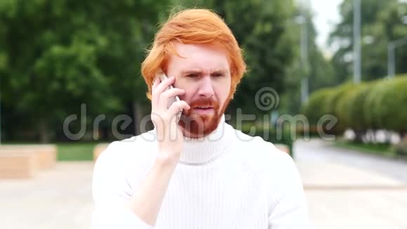 愤怒的红发男人在工作时打电话在户外视频的预览图