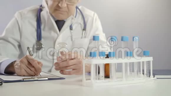 男医生拿着药罐用银笔在工作台上开处方视频的预览图