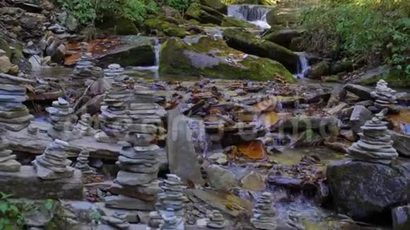 在喜马拉雅山上流动的河岸上有着平衡的禅石结构的山河纯森林溪视频的预览图