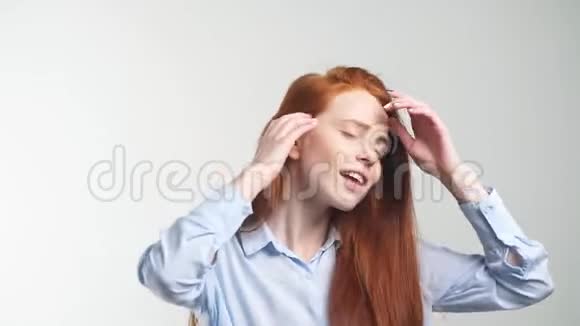 开朗的年轻红发女孩跳舞看着白色背景的相机视频的预览图