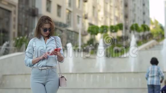 美丽优雅的女人在喷泉背景下使用电话视频的预览图