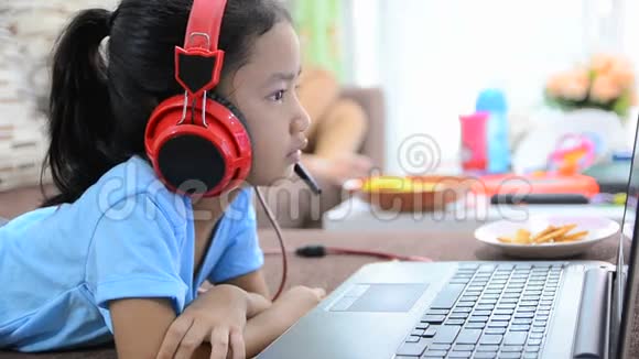 在家中使用笔记本电脑和耳机的亚洲小女孩特写镜头视频的预览图