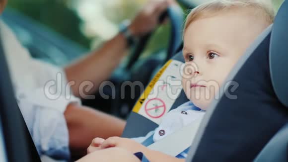 一个小男孩坐在靠近他父亲的汽车座位上开心地笑着概念安全和护理视频的预览图