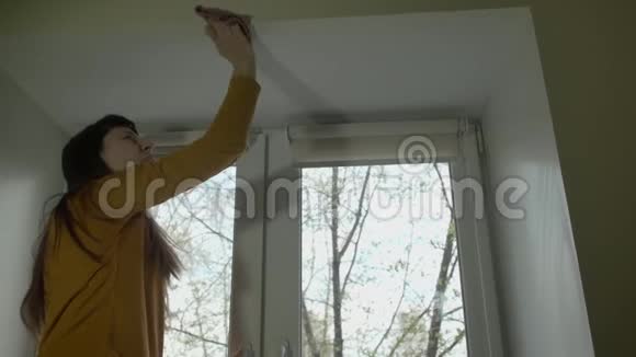 春天的一天黑发女人在塑料窗户上擦拭天花板视频的预览图