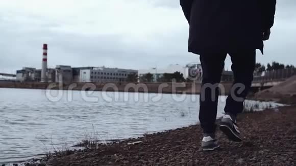 穿着时髦运动鞋在城市岩石海岸行走的人的腿视频的预览图