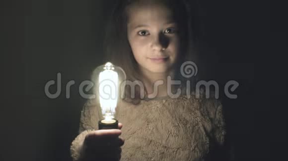 一个有钨丝的灯泡在一个女孩手中亮起视频的预览图